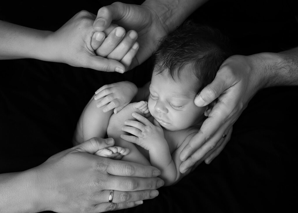 "adorable black and white image of newborn baby in parents hands, sowing love and connection