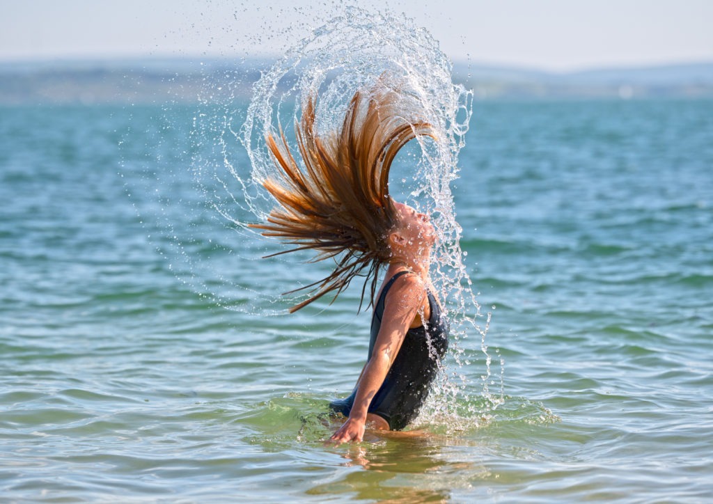 woman in the sea at beach doing a hair flick in the sea