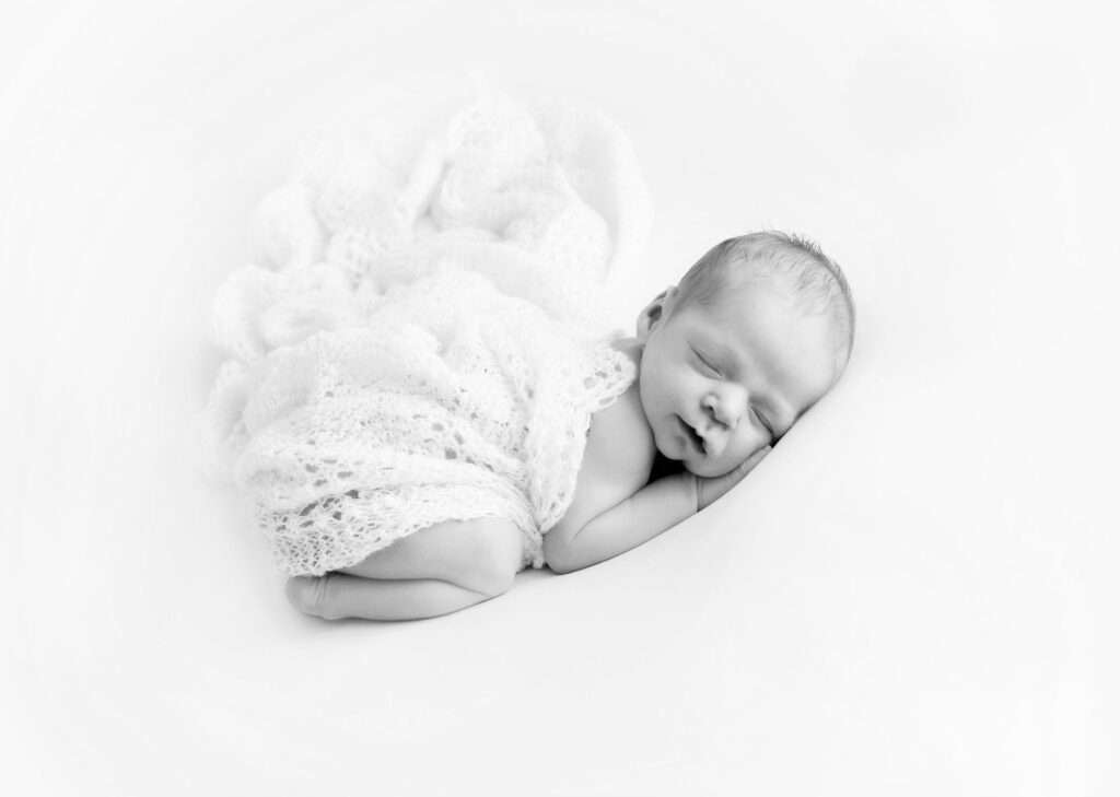beautiful newborn baby posed asleep with blanket