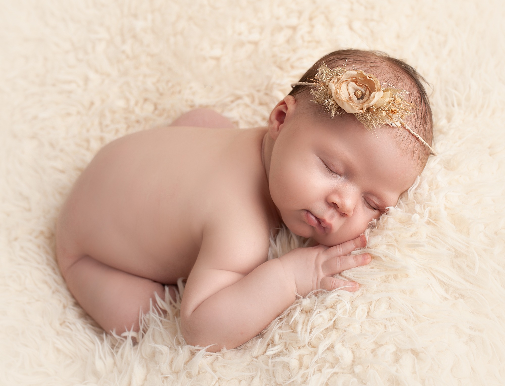 cute sleeping newborn baby girl posed on cream rug 
